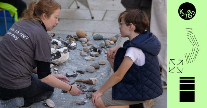 En dame og en ung gutt snakker om steinlignende gjenstander som ligger på et bord.