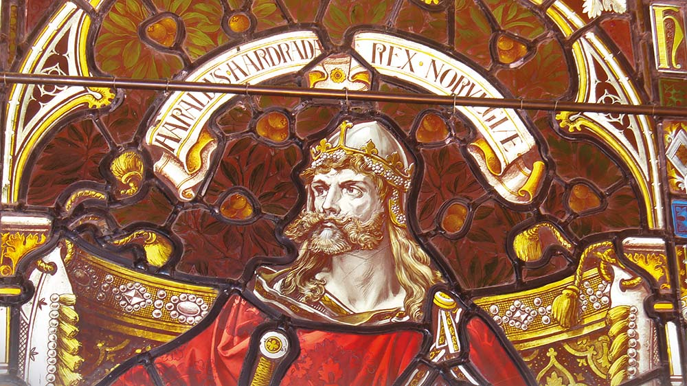 Glassmaleri i farger som viser en viking med hjelm og sverd.