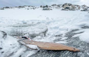The ski is dug out from the snow and the ice is chipped away.
