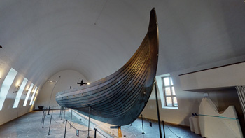 Et vikingskip står utstilt i et rom.