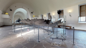 Deler av et vikingskip står utstilt i et rom.