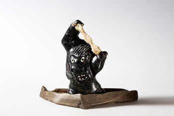 Skulpturen forestiller en sjaman, angakok , som uttrykker sinne over sine hjelpeånder som nekter å skaffe ham mer olje. Derfor er han plassert på en tradisjonell spekklampe. Kunstner: Uriash Puqiqnaq.&amp;#160;UEM49190