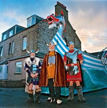 På&amp;#160;vei fra skipsverkstedet tidlig om morgenen, under feiringen av &amp;#160;Up-Helly-Aa . Kostymene er (fra venstre til høyre) fra 1999,1979 og 1995. I midten tidligere &amp;#160;Egil Skallagrimson . Shetland 2001 /&amp;#160;Leaving the Gallyshed, Up-Helly-Aa. Costumes from 1999, 1979, 1995, in the middle a former Jarl who played the part of Egil Scallagrimson. Shetland 2001.