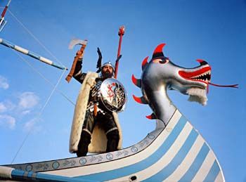 We Axe for What We Want . &amp;#160;Guizer Jarl 2001, Michael Groat, ombord på&amp;#160;skipet sitt &amp;#160;Old Faithful . Han personifiserer vikingen Gunnar Hamundarson av Hildarend fra Island. Gunnar var berømt for å&amp;#160;kunne hoppe så&amp;#160;langt som sin egen høyde i full utrustning, bruke tre sverd samtidig og svømme som en sel. Den ekstra masten med den røde trehånda i toppen refererer til historien om to vikingjarler som seilte om kapp til ei øy. Den som første berørte land hadde vunnet, og kunne gjøre krav på&amp;#160;øya. Den ene vant seilasen ved å kappe av seg hånda med en øks og kaste den på&amp;#160;land. Shetland 2001 /&amp;#160;"We axe for what we want!" The Guizer Jarl 2001, Michael Groat, on board his galley Old Faithful. Groat has taken the persona of the famous Viking Gunnar Hamundarson of Hildarend, Iceland, famed for jumping his own height in full armour, using three swords at one time, and swimming like a seal. The extra mast, with the red wooden hand on top, represents a saga of two Norse jarls racing in separate boats to claim an island as his own. The winner was to be the first to touch the land. However, one of the jarls won the race by cutting off his own hand with an axe and throwing it ashore.Shetland 2001.